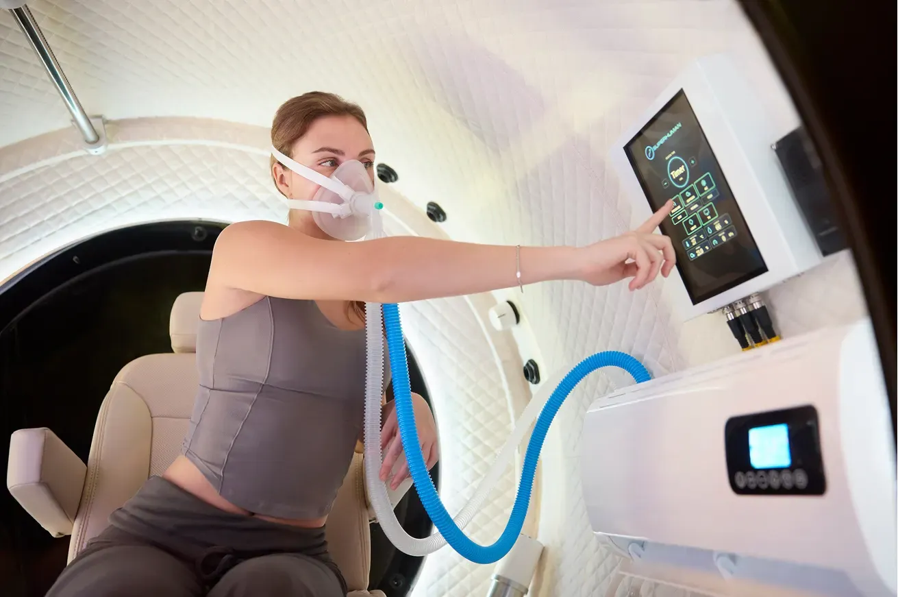 A woman wearing an oxygen mask, using the control screen inside the Superhuman X