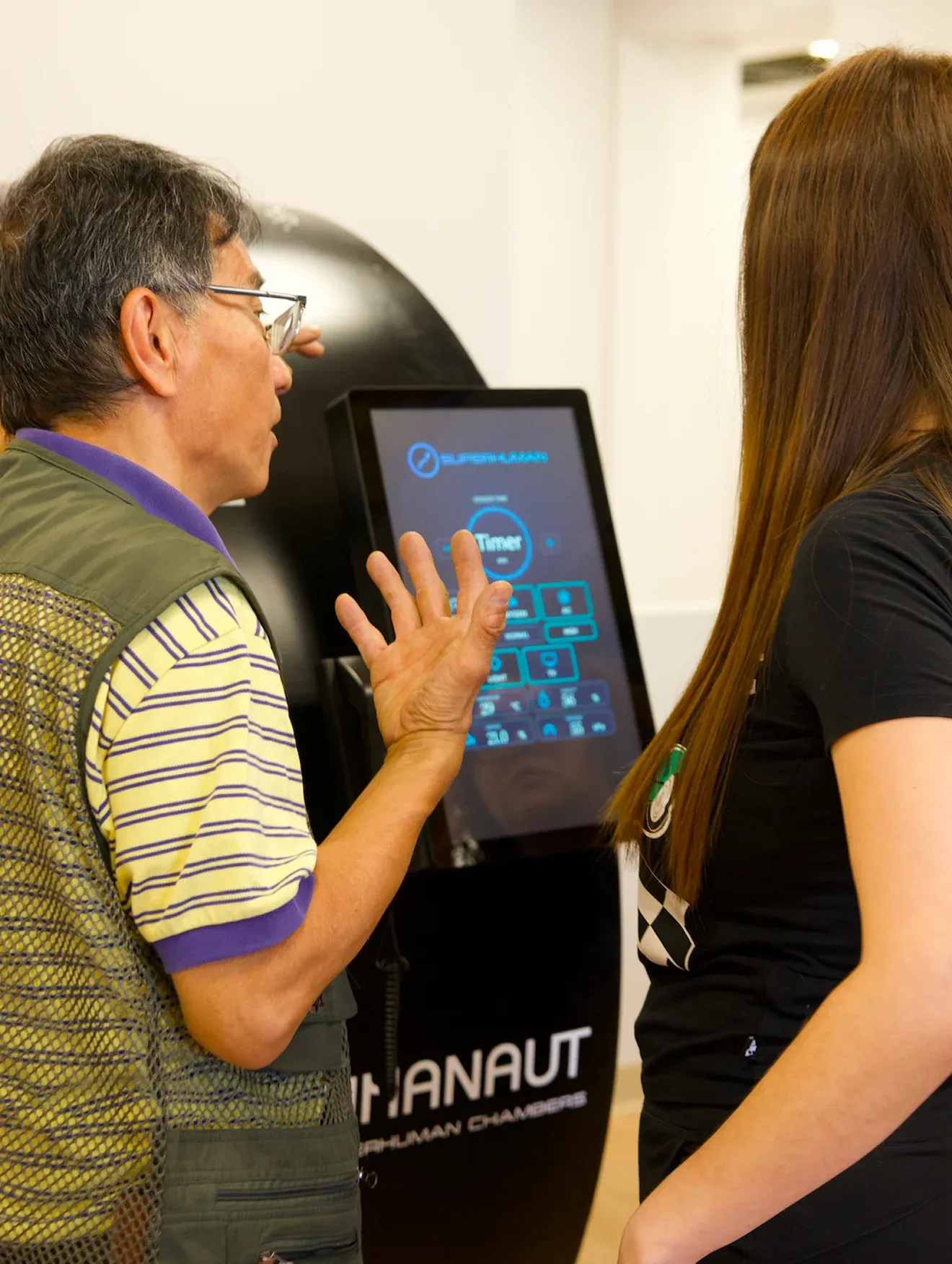 A Superhuman specialist talking a client through the session controls on a chamber touchscreen