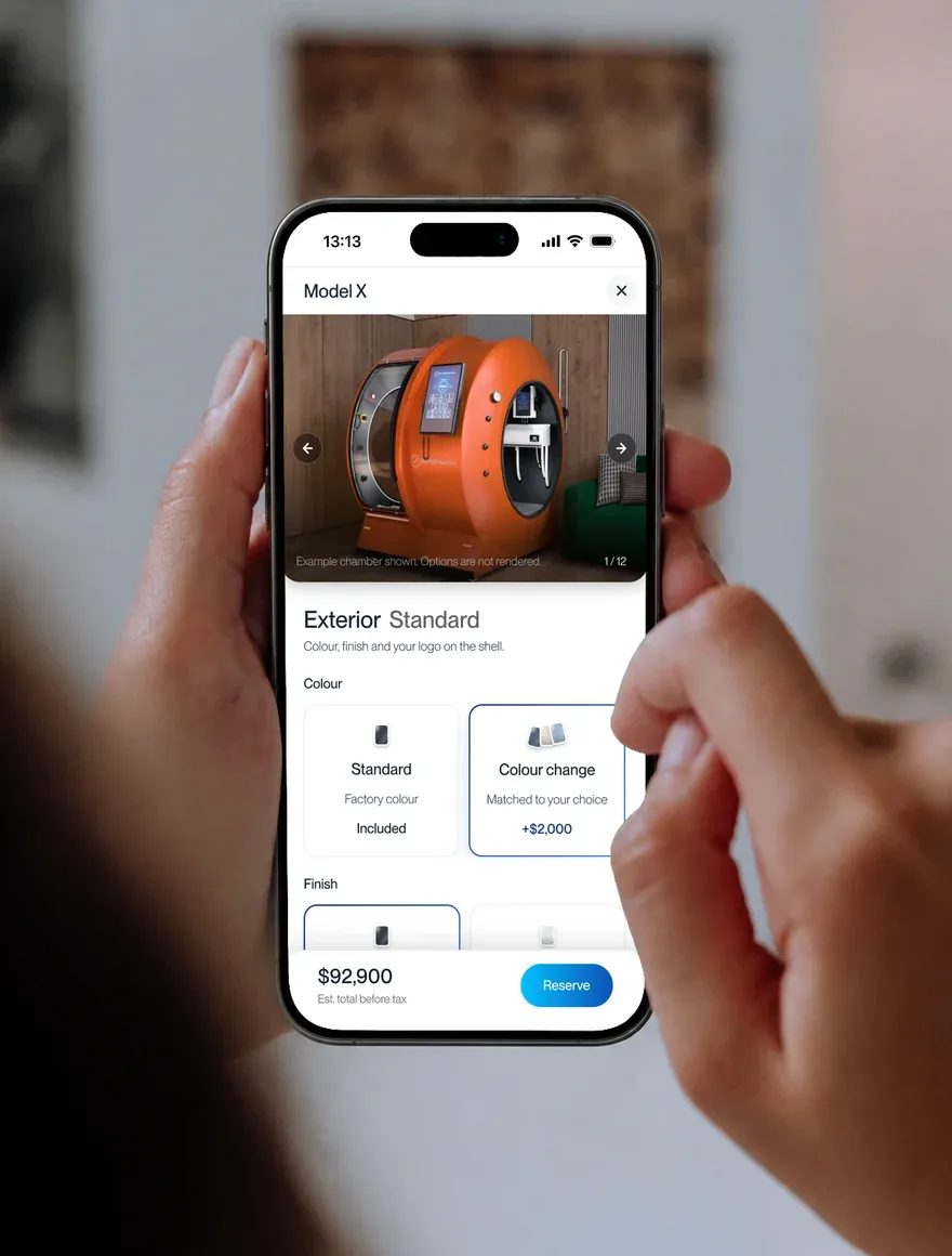 A hand holding a phone with the X configurator open on an orange chamber