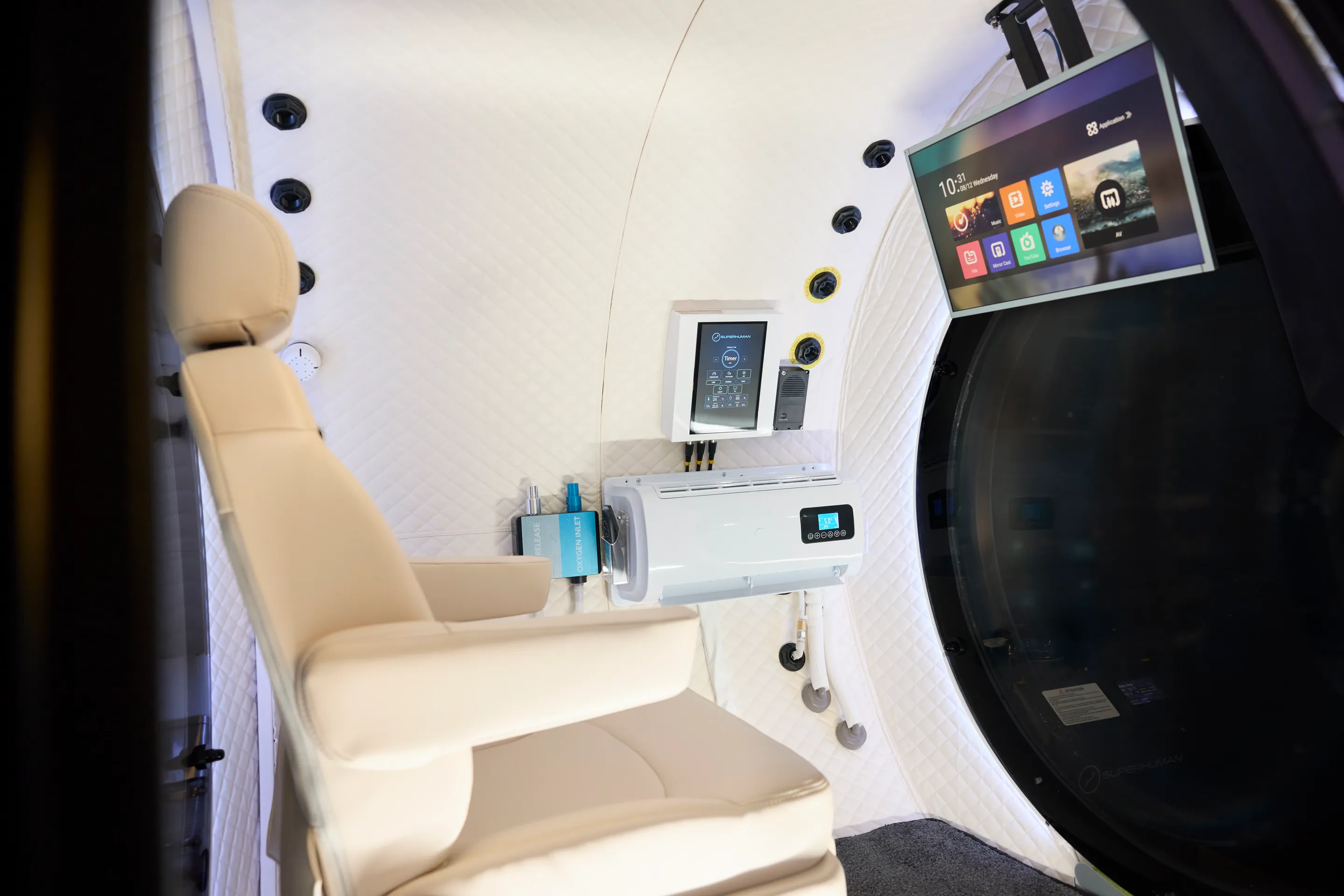 The empty X interior: the cream recliner, the control screen above the cooling unit and the TV by the open door