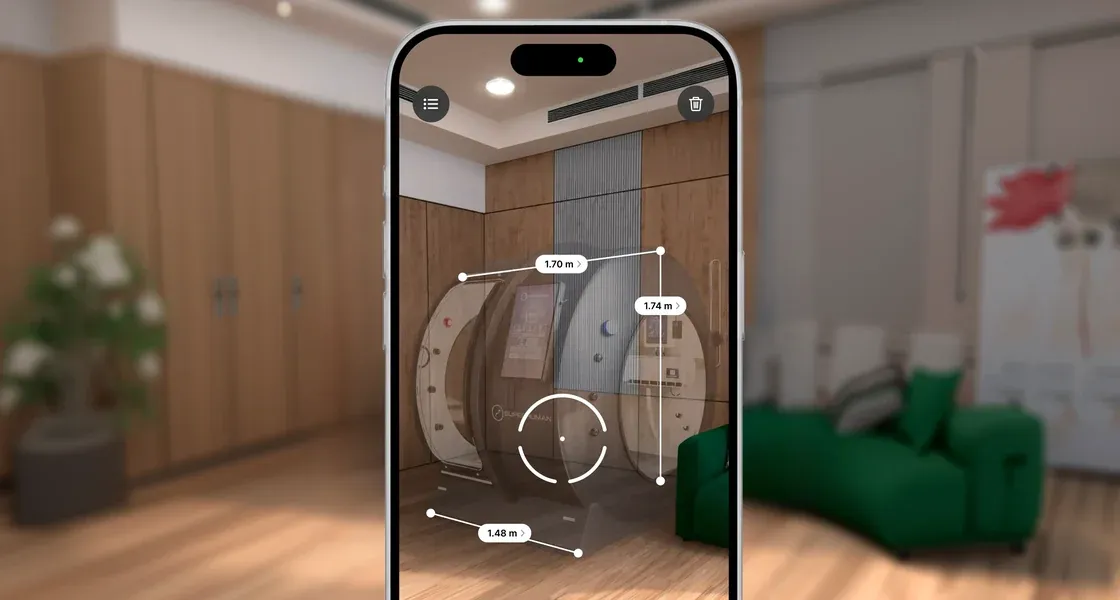 A phone held up in a living room, showing the X placed to scale in augmented reality