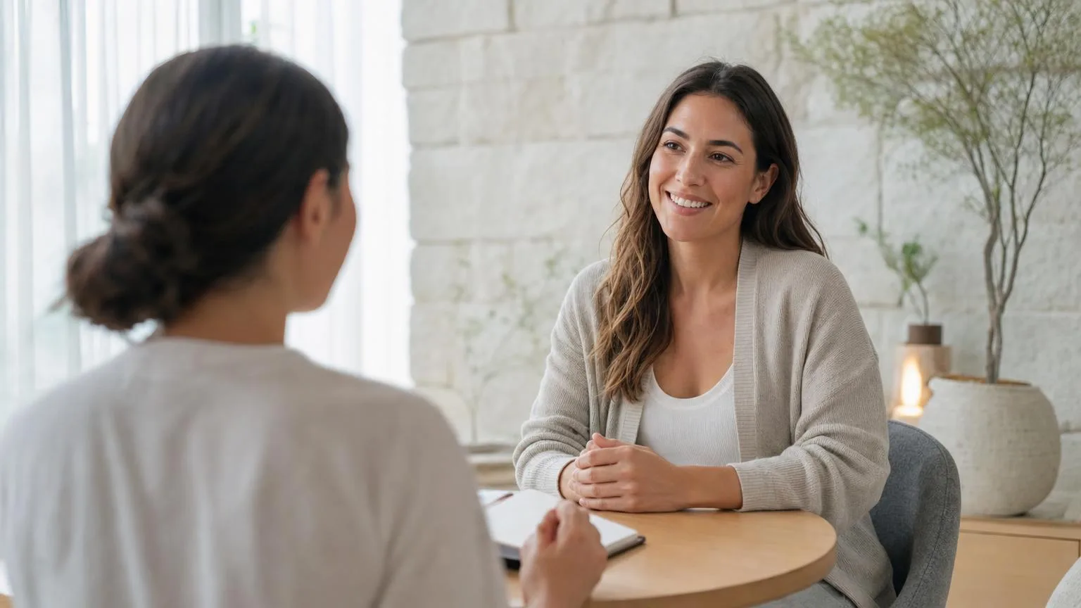 Smiling wellness consultant in conversation with a client across a small round table